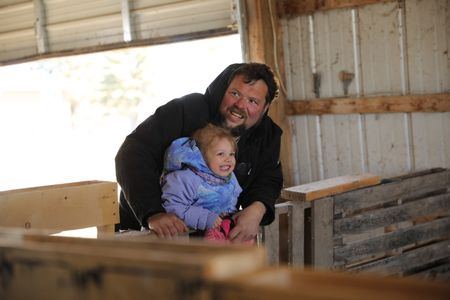 Charles Pol and Abigail Pol smile by the Merino sheep's newly born babies at the Pol family's farm. (National Geographic)