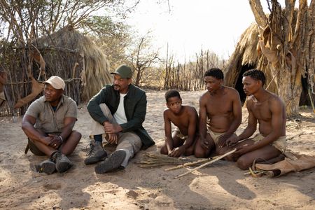 San Bushman Guide Kane Motswana, left, and Will Smith watch sit with the San people just before they teach them how to start a fire in the Kalahari Desert.  (credit: National Geographic/Kyle Christy)