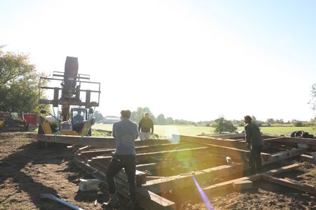 Andrew Hutton, drives a telehandler as Scott Brady, Charles Pol, and Ben Reinhold help guide and stack the lumber from the old barn. (National Geographic)
