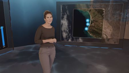 Dr. Diva Amon next to a GFX map with the particular shark attack locations pinpointed. (National Geographic)