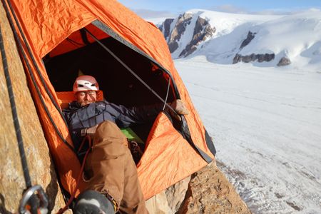 Expedition Safety and Logistics lead, Aldo Kane, rests his eyes for a moment in a portaledge on Pool Wall in Eastern Greenland.  (photo credit: National Geographic/Matt Pycroft)