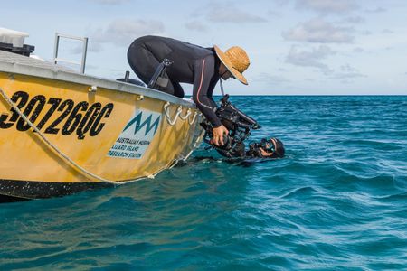 Camera Assist Woody Spark passes an underwater camera system to Director and Cinematographer, Adam Geiger, in the water. (National Geographic for Disney/Harriet Spark)