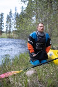 Professional kayaker Ben Stookesberry kneels by the river with his kayak and paddle.  (National Geographic/Harrison Gayton)