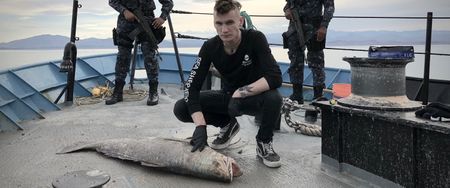 Jack Hutton investigates a dead totoaba with two Mexican navy officers standing guard. (photo credit: National Geographic)