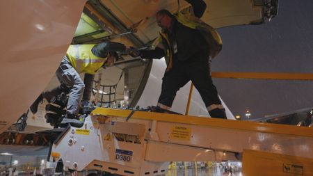 Jim Gaspar, Ground Support Equipment Mechanic at Air Canada, helps a ramp agent out of an aircraft cargo hold. (Arrow International Media Ltd & Cantina Media)