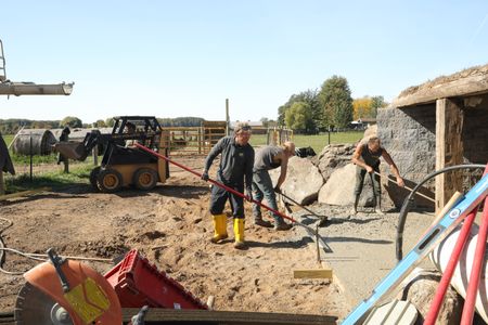 Ben Reinhold, Seth Doble, and Scott Brady level out the wet concrete they are using for the sheep hut's flooring. (National Geographic)