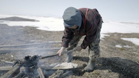 John Pingayak builds a fire for their family meal. (National Geographic/Matt Kynoch)