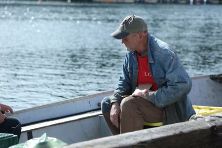 Sam Carlson measures his friends skiff, in advance of constructing a new fairlead for the boat. (National Geographic/Wayne Moss)