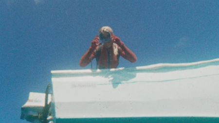 Valerie Taylor leaning over the boat looking into water in 1968. Shot from underwater. (photo credit: Ron & Valerie Taylor)