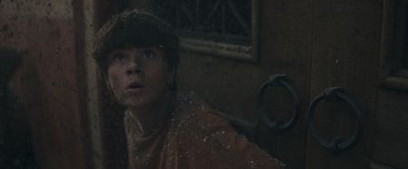 Avianius, played by Frankie Treadaway, clings to a doorway in the street at Pompeii, looking up in fear at Vesuvius, as thick volcanic ash rains down around him. (National Geographic)