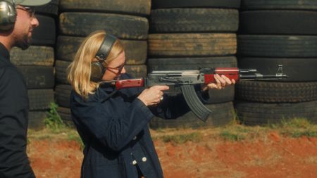 Jose watches as Mariana van Zeller aims a gun at bullet-proof glass in Johannesburg, South Africa. (National Geographic)