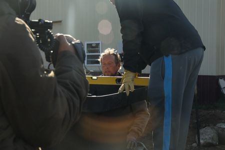 A crew member films Ben Reinhold looking at a spirit level, held by Charles Pol, to level out the water tank and ground for the Pol family farm's pond. (National Geographic)