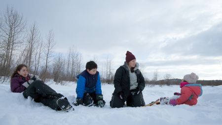 Sonta Roach teaches her children, Ryder, Sydney, and Chevelle about rabbit snaring. (BBC Studios/Dwayne Fowler )