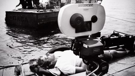 Steven Spielberg lies on a dock next to a camera on the set of Jaws. (Courtesy of Universal Studios Licensing LLC)