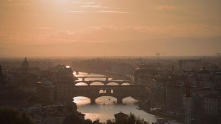 Scaenic aerial view of the sun setting over Florence’s Arno River, casting a golden glow on its iconic bridges, with Ponte Vecchio in the foreground.  (credit: National Geographic)
