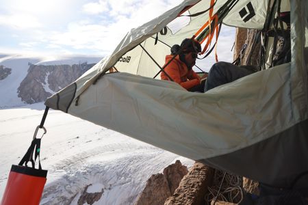 Dr. Heidi Sevestre makes notes while relaxing in a portaledge on Pool Wall in Eastern Greenland.  (photo credit: National Geographic/Matt Pycroft)