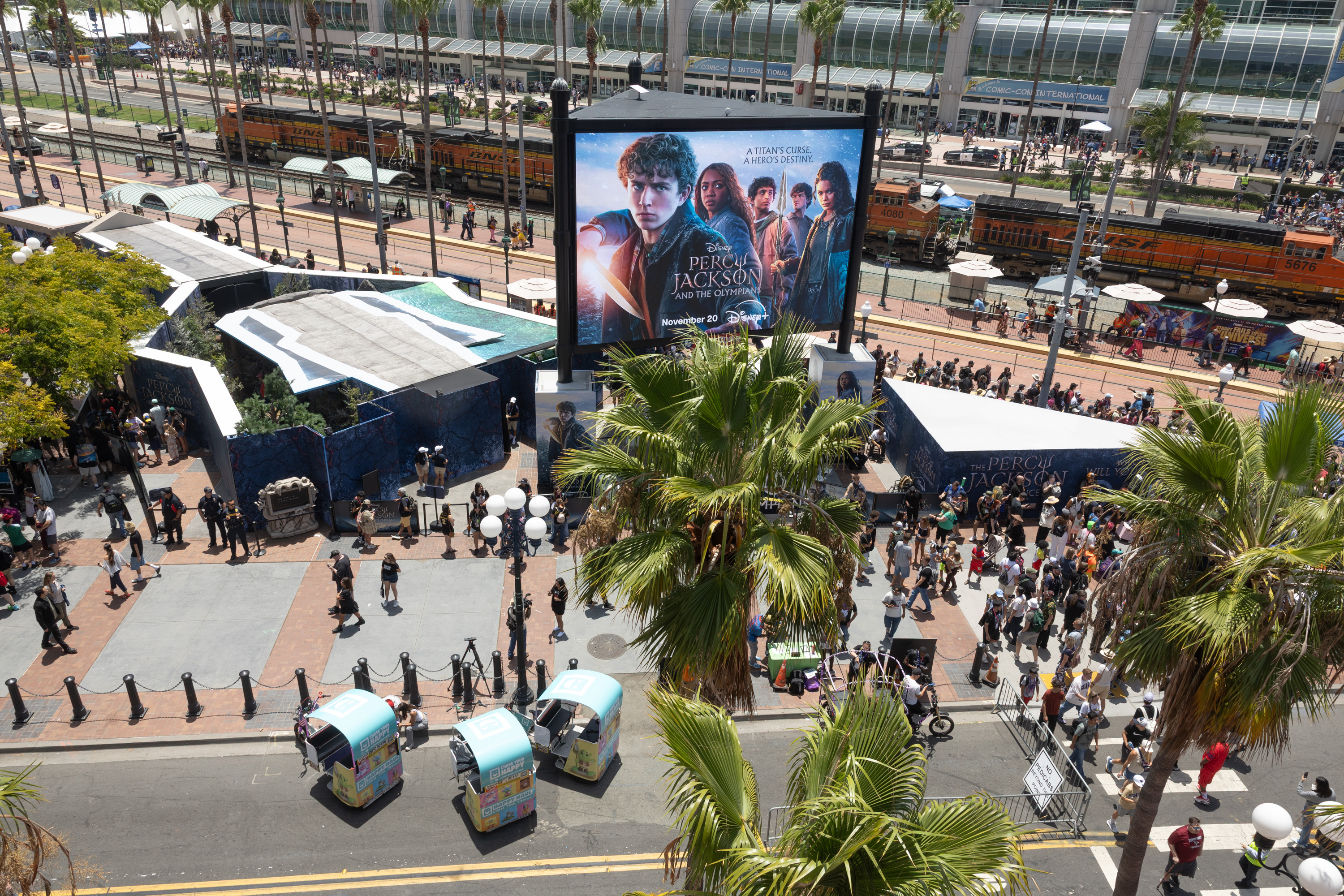 Percy Jackson and the Olympians cast at Comic-Con 2026 activation – Walker Scobell, Aryan Simhadri, Tamara Smart and others posing in front of official backdrop