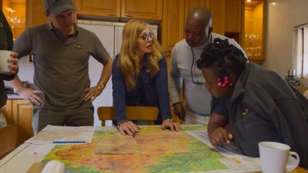Shannon Hoffman and colleagues study maps together around a kitchen table. (National Geographic)