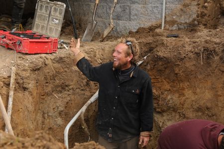 Ben Reinhold smiles while standing in a hole in the Pol family farm's sheep hut, with his employees and Charles Pol, to move the water pipe and provide better drainage of the sheep's excrements. (National Geographic)