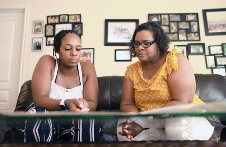 Desare' Allen and Salena James look at pictures and memorabilia about their great uncle Doris Miller in Flosetta Miller's home in Arlington, Texas. "Erased: WW2's Heroes of Color" tells the stories of three Black heroes who miraculously survived the attack on Pearl Harbor. One of these men, mess attendant Doris Miller, defied racial stereotypes when he shot down enemy planes during the attack. (National Geographic/Nelson Adeosun)