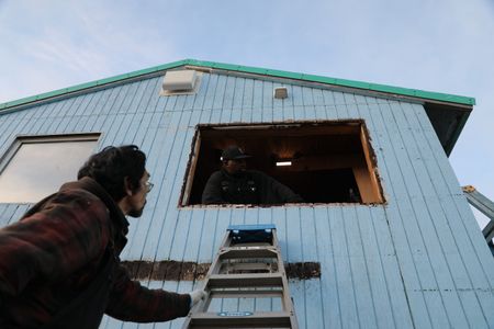 Marvin Agnot and Glyndaril White, Jr. rebuild the side of Marvin's home that was damaged due to old age and rot. (National Geographic/Lauren Bird Dixon)
