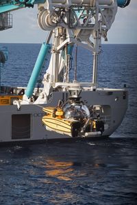 A submarine is lowered by crane into the water. (National Geographic/Paige McGarvin)