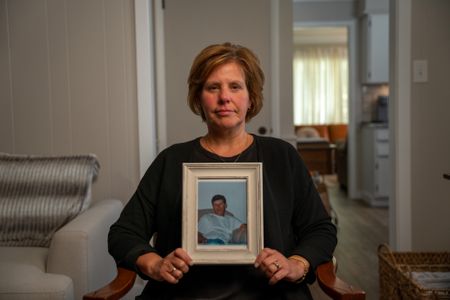 Denise Santille holds a photo of her half-brother Michael Leach. (National Geographic/Andrew Thompson)