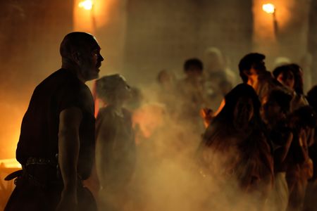 The Praetorian, played by Barry Aird, and Helvia, played by Christina Cole, stand on the smoky shore of Herculaneum, looking on as as citizens queue to evacuate by boat. (National Geographic/Darrin Zammit Lupi)