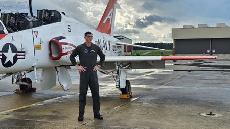 Student 1st LT Austin Claggett poses in front of a T-45 after it is hosed down. (National Geographic/Lyndsi Gutierrez)