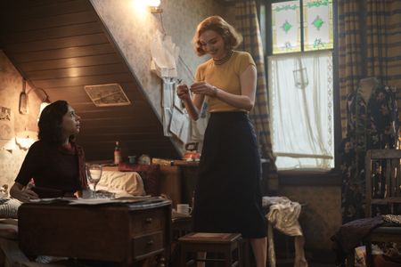 A SMALL LIGHT - Miep, played by Bel Powley, is gifted a necklace by her friend Tess, played by Eleanor Tomlinson, as seen in A SMALL LIGHT. (Credit: National Geographic for Disney/Martin Mlaka)