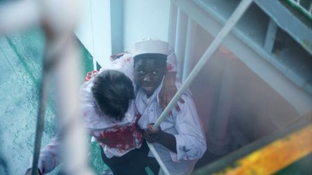 Mess attendant Doris Miller (played by Abdul Sulaiman) helps an injured officer in a WW2 historic reenactment scene for "Erased: WW2's Heroes of Color. The series tells the stories of three Black heroes who miraculously survived the attack on Pearl Harbor. One of these men, mess attendant Doris Miller, defied racial stereotypes when he shot down enemy planes during the attack. (National Geographic)