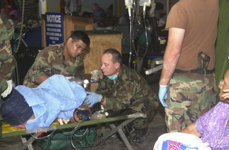 Two miliary members attend to person lying on a cot in the Superdome after Hurricane Katrina, in New Orleans, La. (Ed Bush)