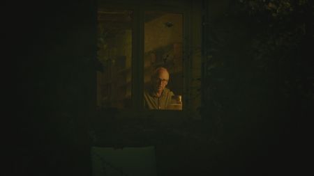 StÈphane Bourgoin is pictured through a window while he works at his desk during the production of "Killer Lies: Chasing a True Crime Con Man," a documentary series about obsession and deception, following the unraveling of  Stephane Bourgoinìs career as a best-selling author and serial killer expert. (National Geographic)