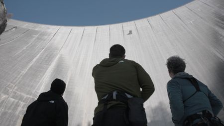 At the base of the Luzzone dam, in Switzerland, Chris, climbing expert Percy Bishton, right, and motocross stunt rider Robbie Maddison, left, talk through the climbing route.  (Credit: National Geographic)