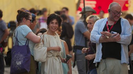 Lubna Azabal (Julia Felix) has her costume adjusted by Costume Designer Cécile Van Dijk in between takes. Makeup Artist Raissa Facciol stands behind Cécile, and 1st AD Tim Bain stands to the right. (National Geographic/Matthew Muscat Drago)
