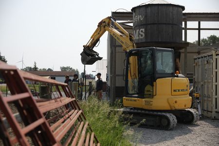 Scott Brady, Max Nordlie, and Sam Korthals fasten a chain to a mini excavator while Andrew Hutton operates it at the Pol family's farm. (National Geographic)