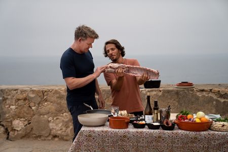 Portugal - Gordon Ramsay (L) and Chef Kiko Martins with a cut of pork during the final cook. (Credit: National Geographic/Justin Mandel)