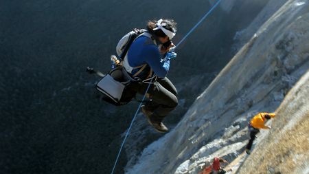 Jimmy Chin (left), using ropes, jumps from a wall to take a photo of two other climbers.  (credit: Jimmy Chin Productions)