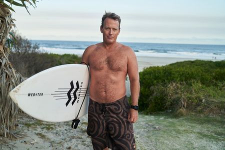 Lee Jonsson with his surfboard at Shelly Beach. (National Geographic/Justine Kerrigan)