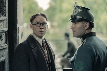 A SMALL LIGHT - Jan Gies, played by Joe Cole, enters an apartment guarded by German soldiers in A SMALL LIGHT. (Credit: National Geographic for Disney/Dusan Martincek)