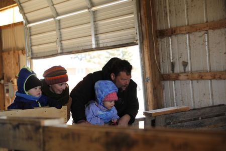 Silas Pol, Beth Pol, Charles Pol, and Abigail Pol look over the lambing pens fence to check on the Merino sheep's new babies. (National Geographic)