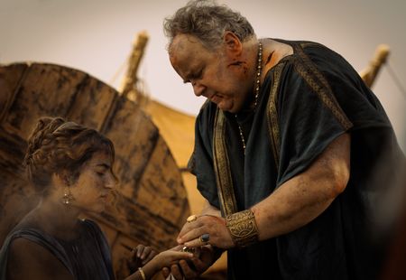At the Pompeii displacement camp, Cassius, played by Robert Bowman, hands the money he owed to Julia Felix to Amalthea, played by Buket Komur. (National Geographic/Darrin Zammit Lupi)
