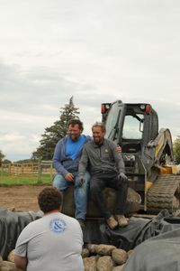 Charles Pol and Ben Reinhold smile while sitting on a rock in front of Andrew Hutton at the Pol family farm's new pond and waterfall. (National Geographic)