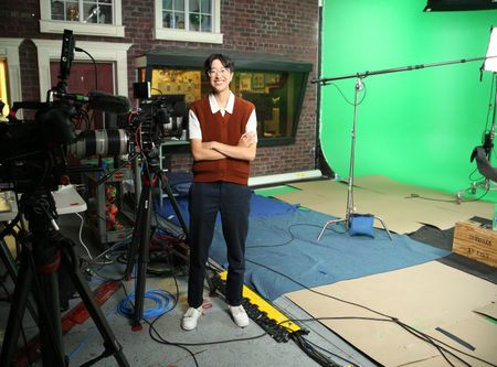 A-Bel Gong standing and smiling with arms crossed next to video equipment. (National Geographic/Robert Toth)