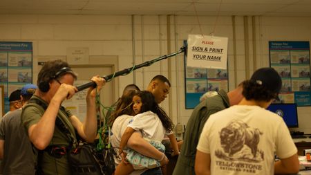 During family day, sound recordist Phil Bax checks his equipment while preparing to film student Captain Micah Nissly and Ariella Nissly. (Credit: National Geographic/Freddie Claire)