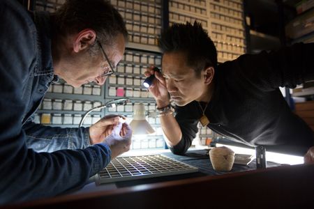Acre, Israel - Dr. Albert Lin (R) observes as Dr. Robert Kool of the Israel Antiquities Authority examines a crusader-era coin. (Blakeway Productions/National Geographic)