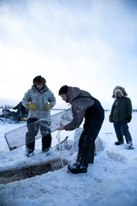 Avery Hoffman lifts their blackfish trap from under neath the ice while his brother, Gage, and mother, Ana, watch. (BBC Studios Reality Productions, LLC/)