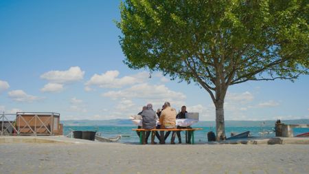 A group of fishermen savors sbroscia soup outdoors, with the scenic backdrop of Lake Bolsena. (credit: National Geographic)