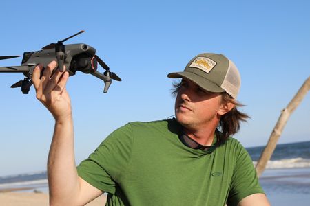 Tim Regan holding up and inspecting his drone on the beach. (National Geographic/Mariana Kneppers)