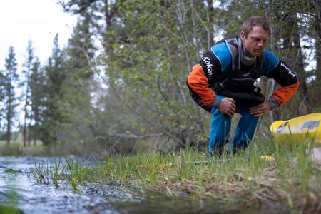 Professional kayaker Ben Stookesberry squats by the water.  (National Geographic/Harrison Gayton)